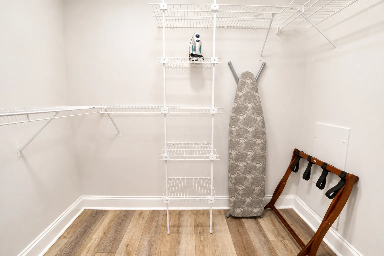 Spacious condo walk-in closet with shelving, iron, and ironing board
