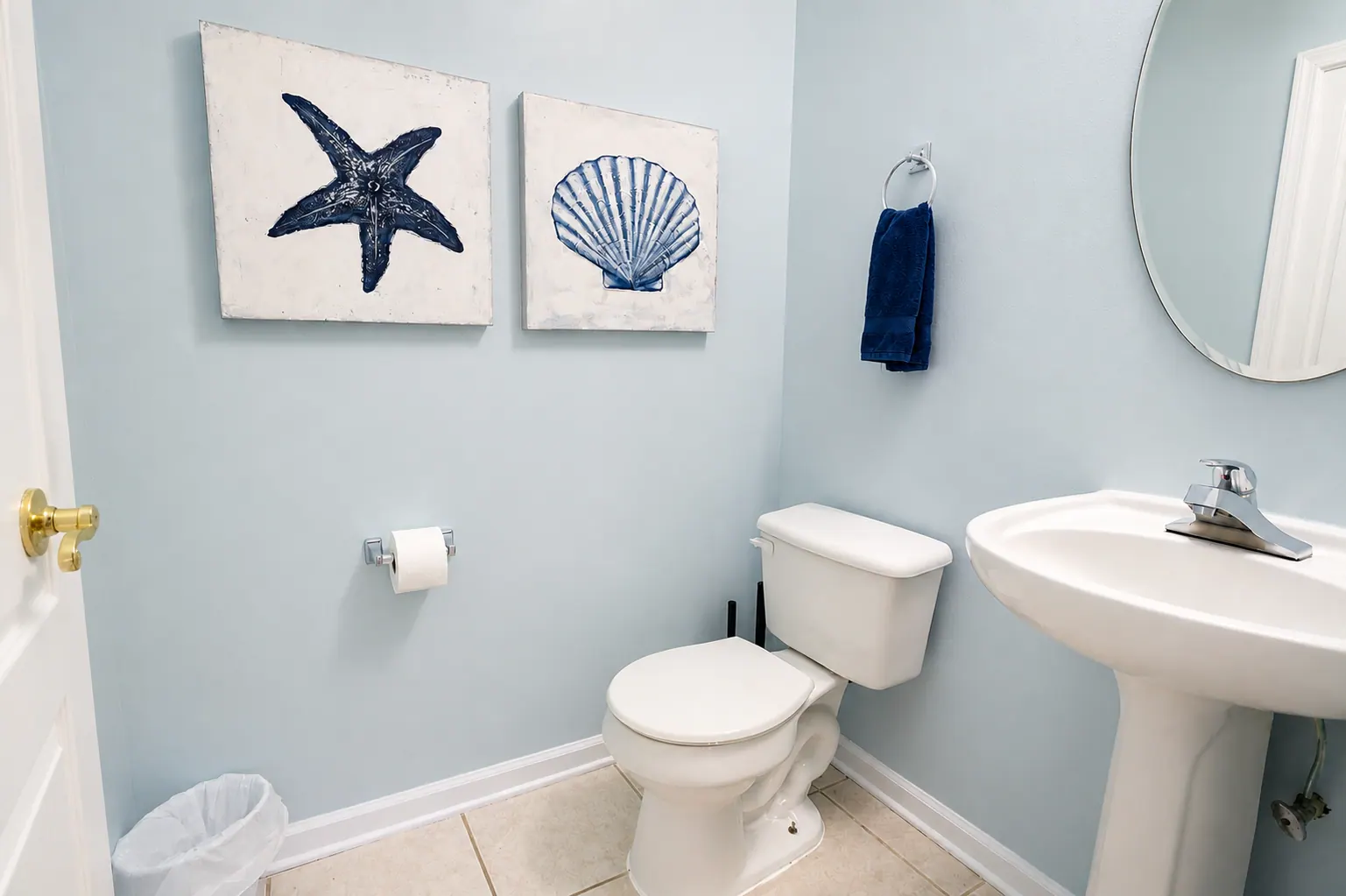 Coastal half bath with starfish and seashell artwork and pedestal sink