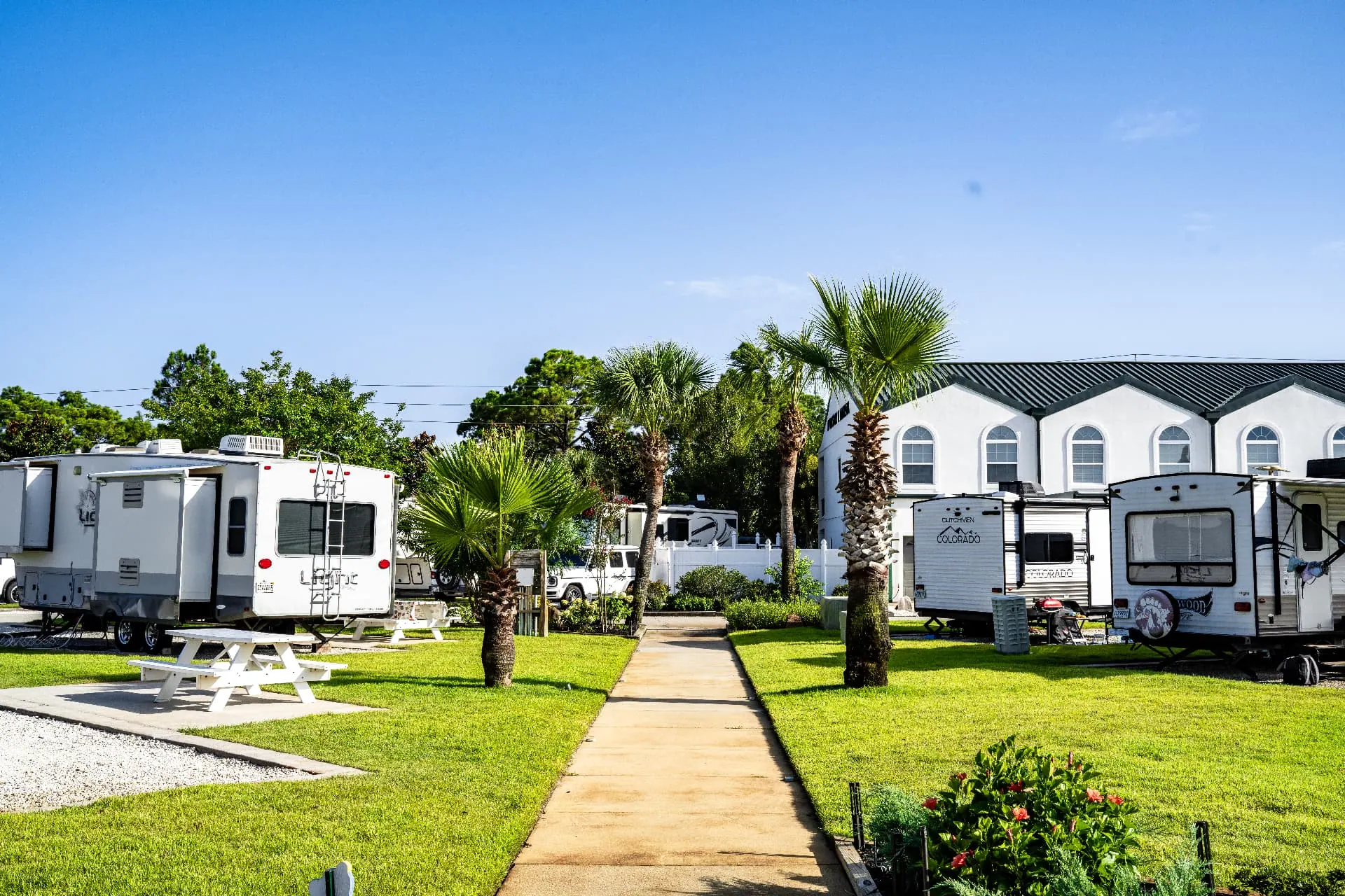 RVs parked under palms along the sunlit resort pathway