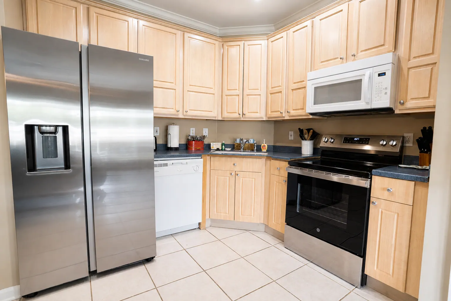 Fully equipped condo kitchen with stainless steel appliances, wood cabinets, and double sink