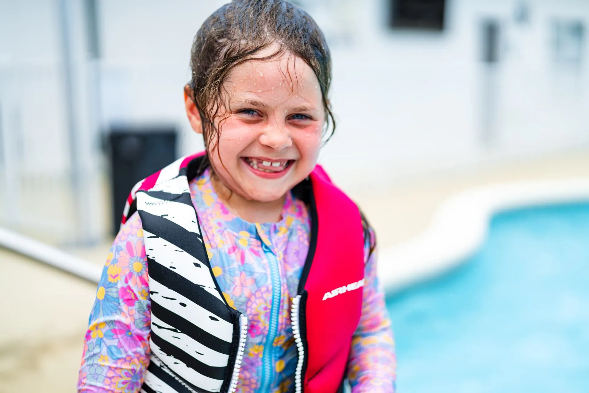 Smiling child in a life jacket by the resort pool