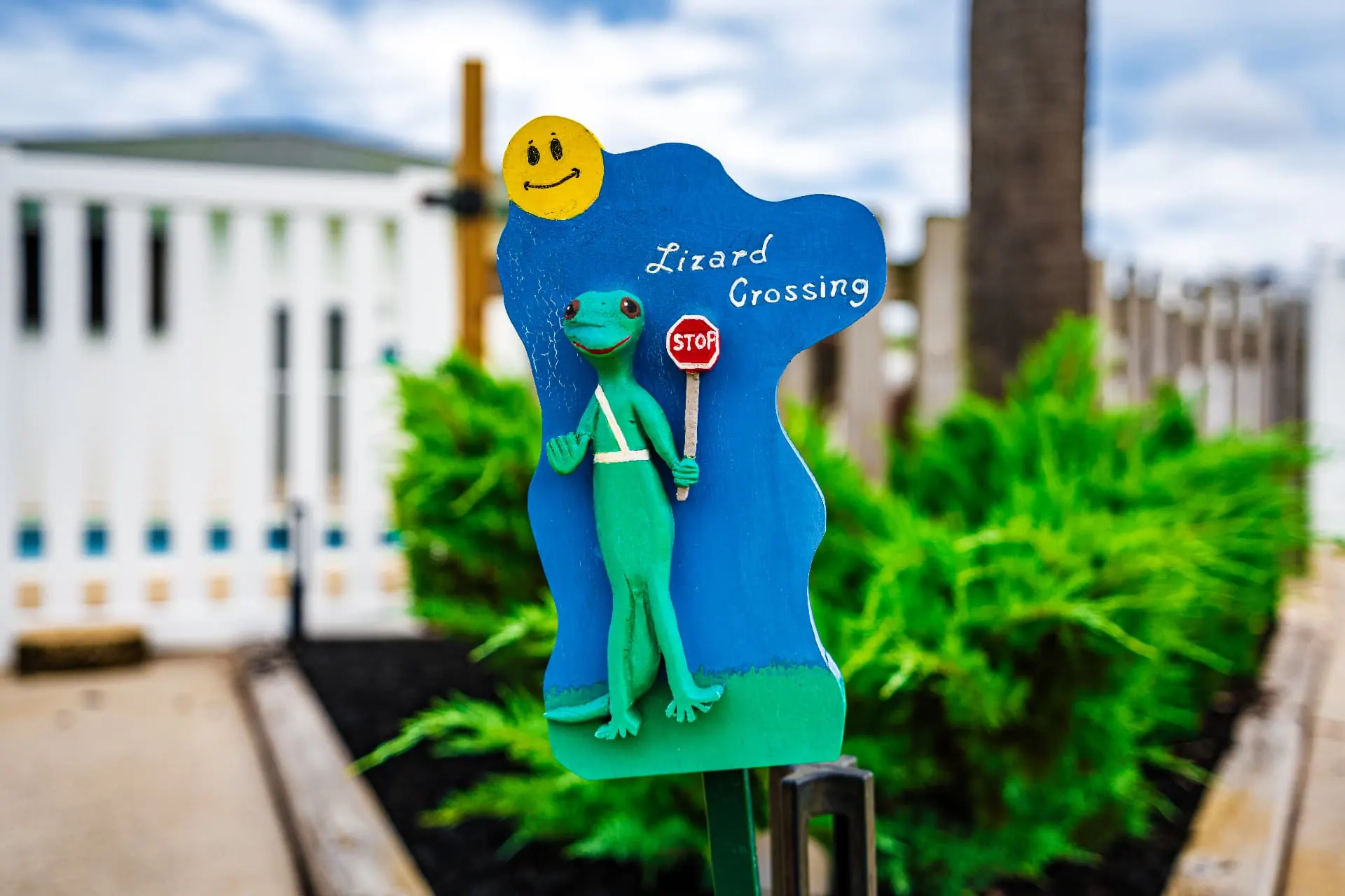 Whimsical hand-painted “Lizard Crossing” sign in a garden beside the resort