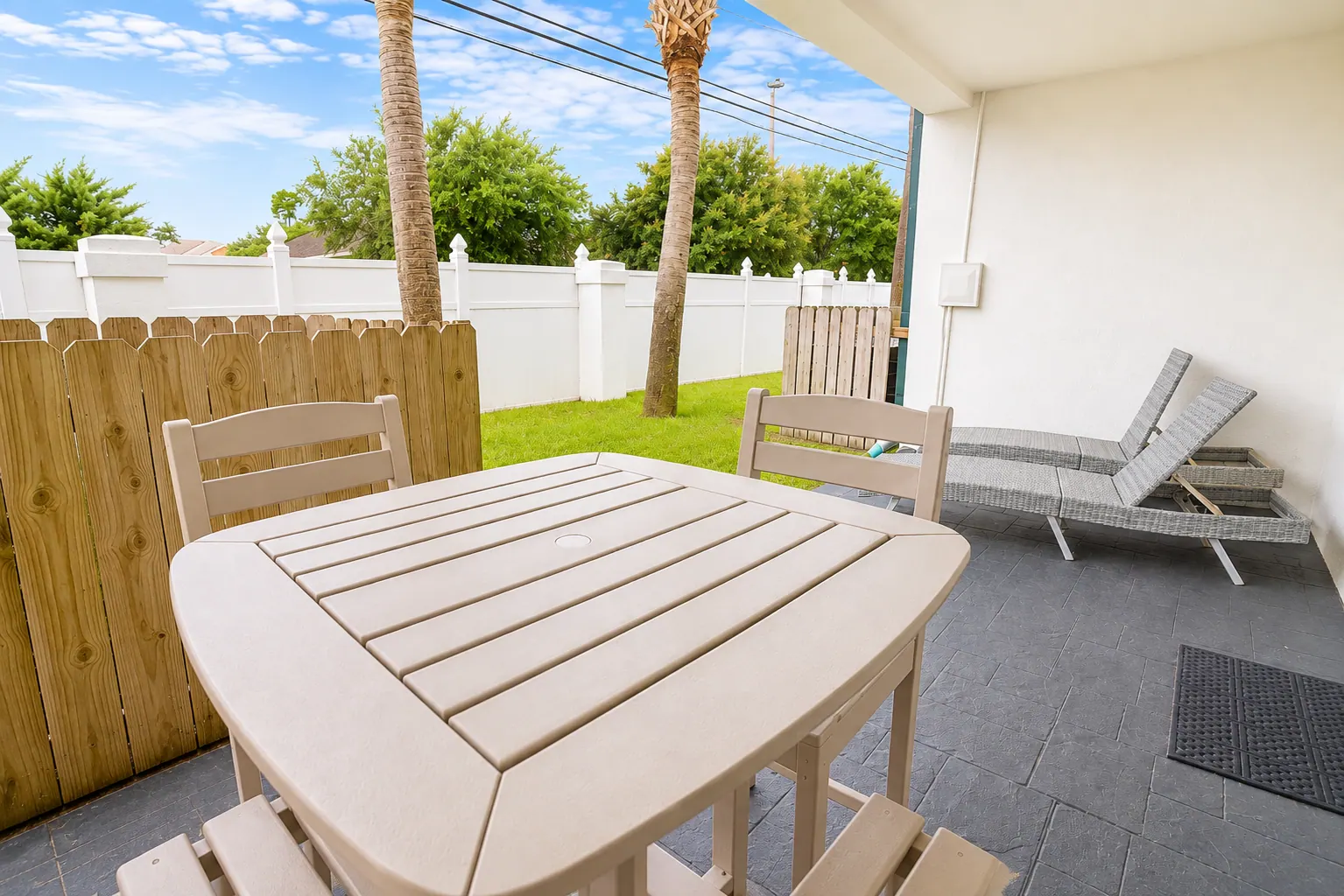 Covered condo patio with a high-top dining table, chairs, and wicker loungers