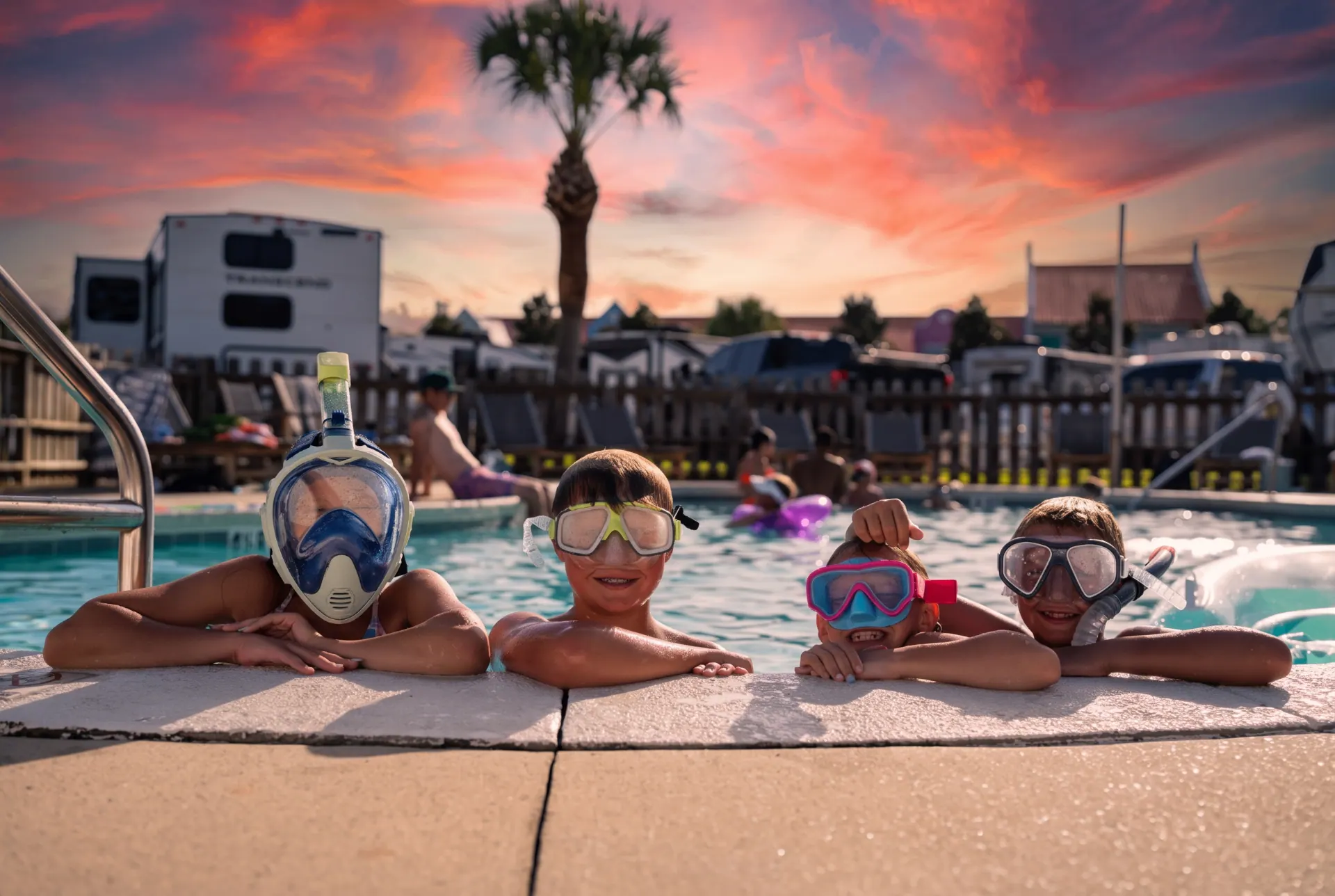 Kids enjoying the heated and chilled resort pool at sunset with RV sites in the background