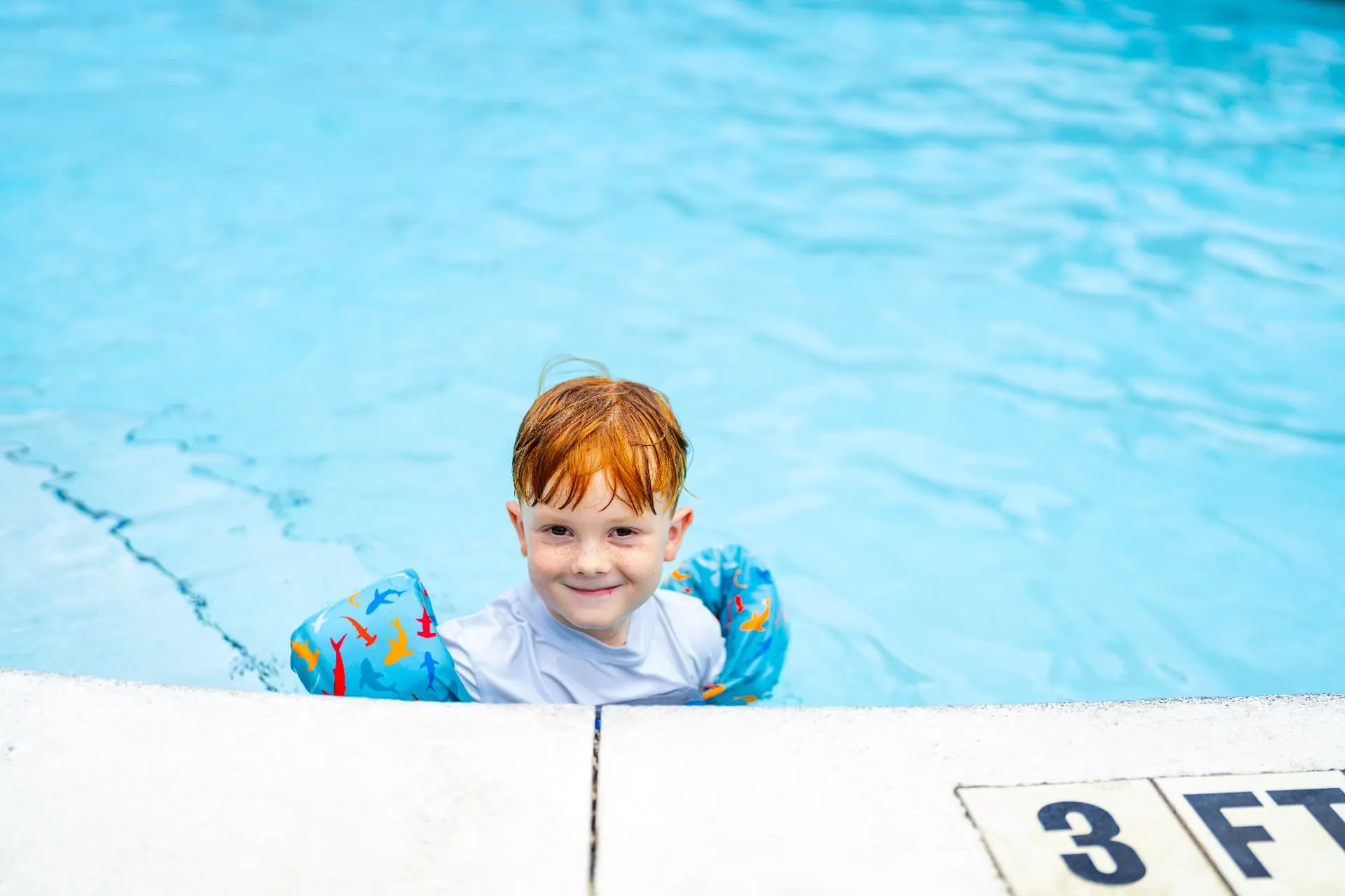 Child swimming in the resort pool wearing shark floaties