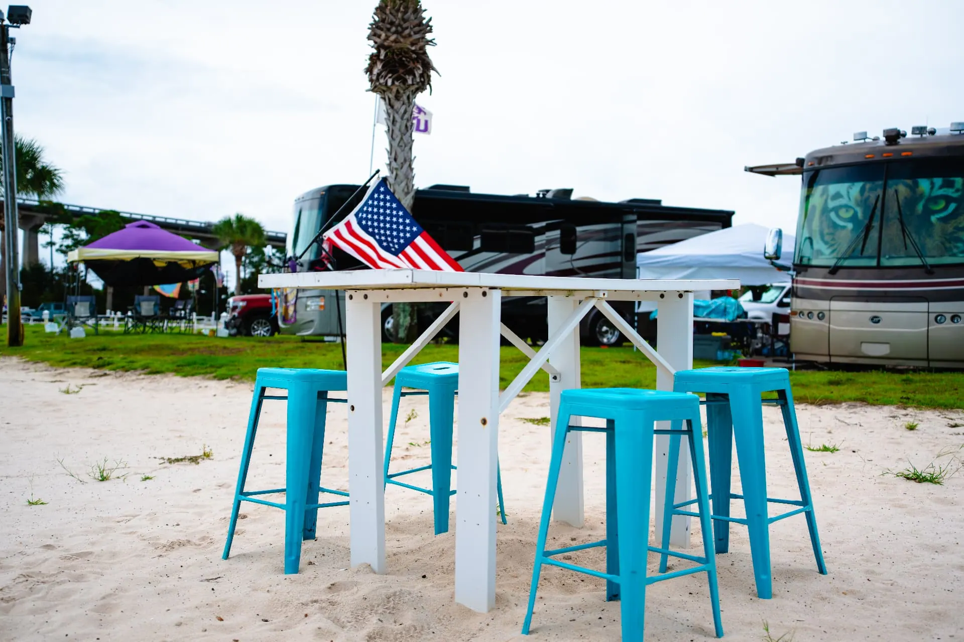 High-top table with teal stools on the sand among the RV sites