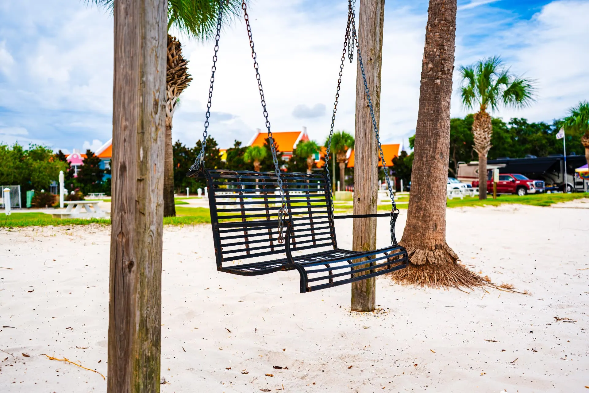 Porch swing hanging between palms on the resort's white sand