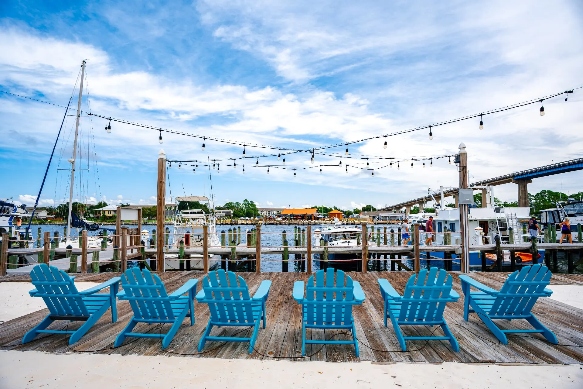 Row of bright blue Adirondack chairs on a deck overlooking the marina and Intracoastal Waterway at sunset