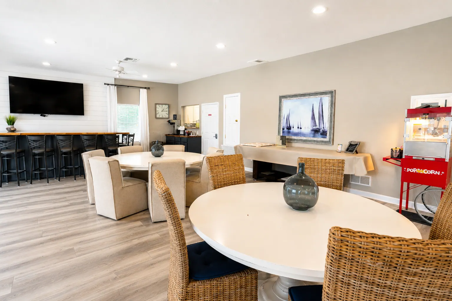 Resort clubhouse with a blue bar, lounge seating, TV, popcorn machine, and sailboat artwork