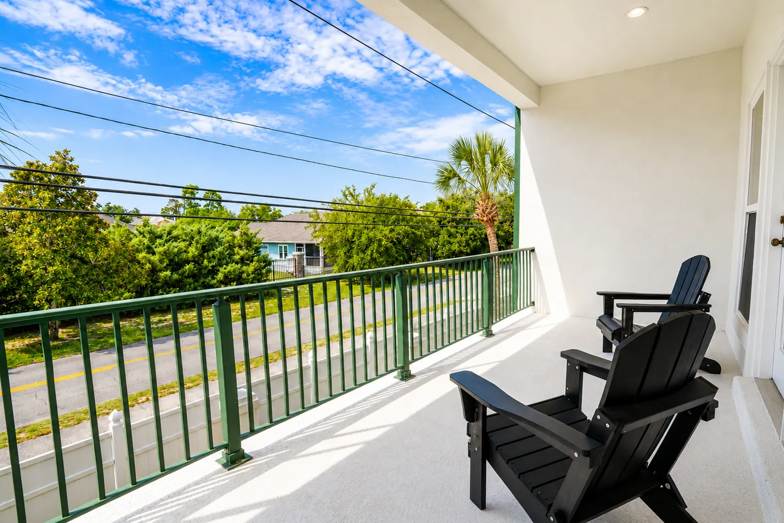 Private condo balcony with black Adirondack chairs and palm views