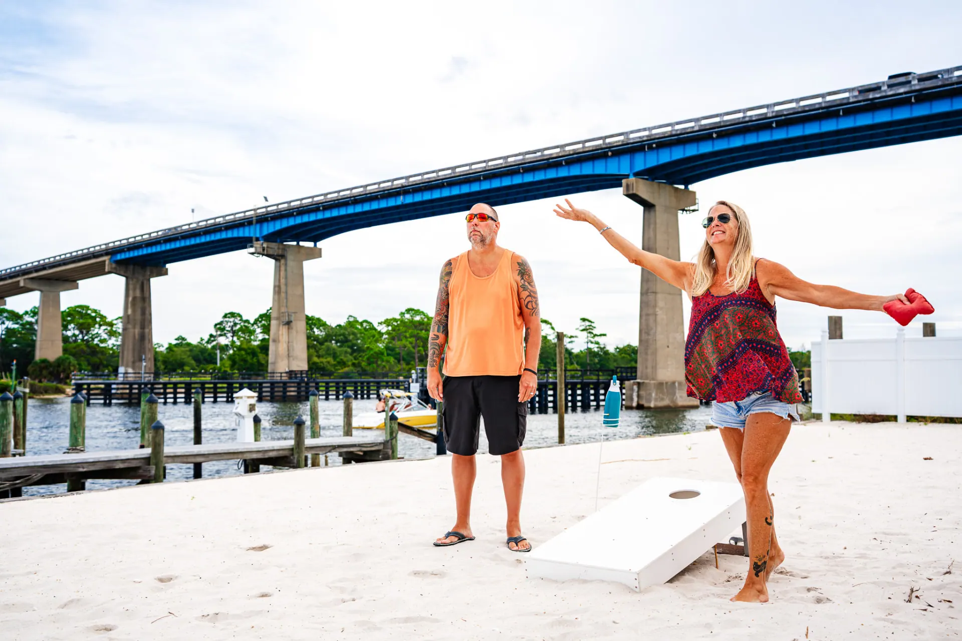 Guests playing cornhole on the sand by the marina