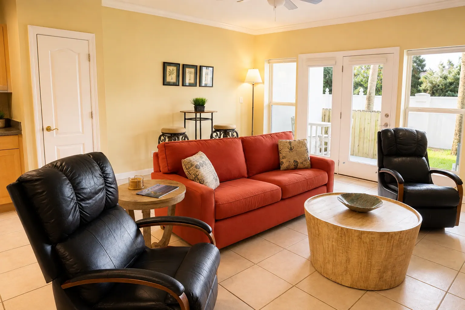 Furnished condo living room with red sofa, leather recliners, and patio doors