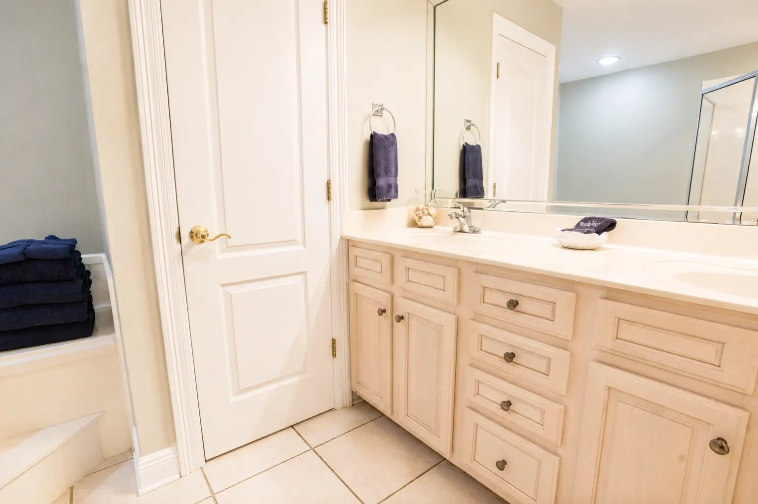 Condo primary bathroom with double vanity, large mirror, and garden tub