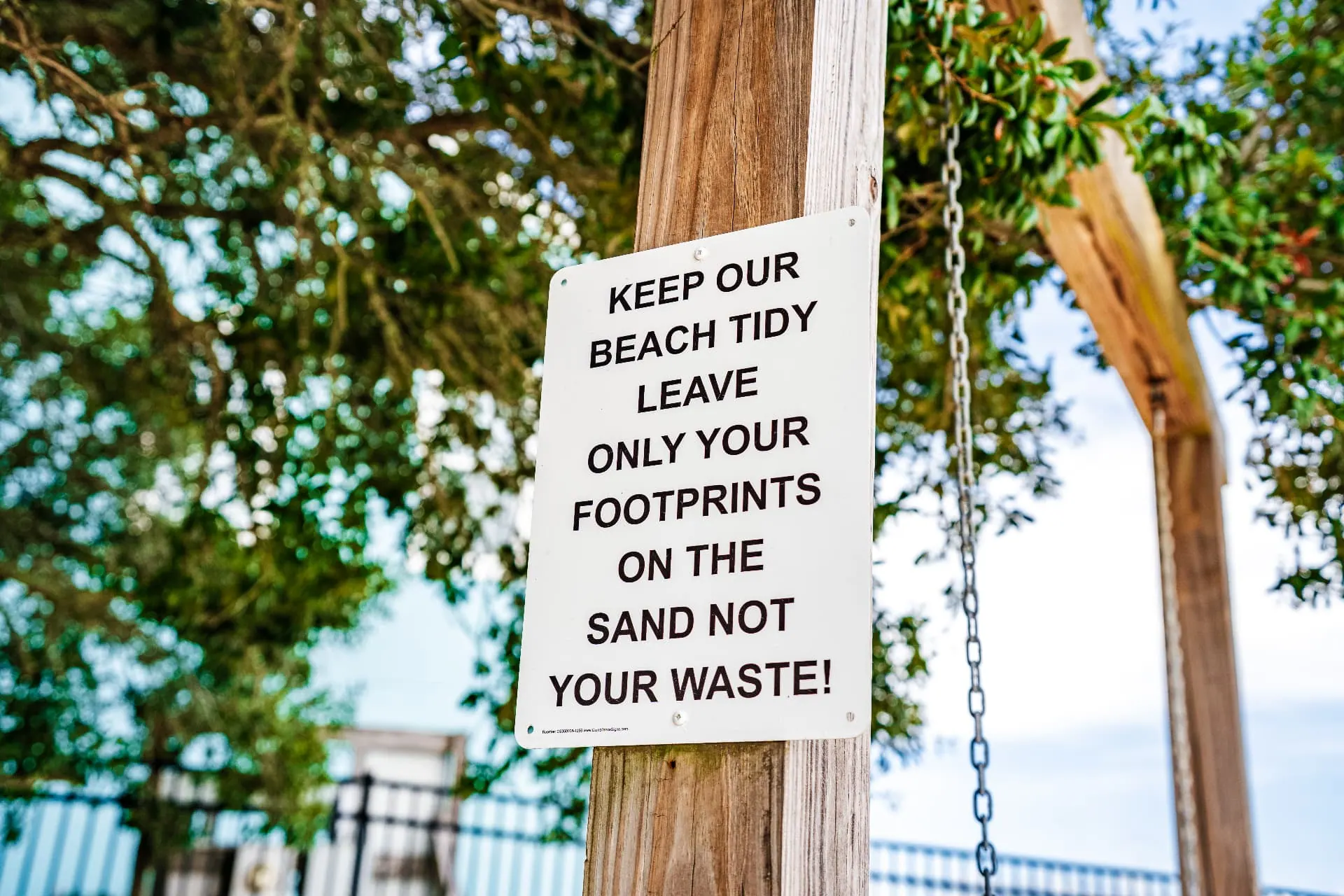 Beach sign reading “Keep Our Beach Tidy — Leave Only Your Footprints On The Sand, Not Your Waste”