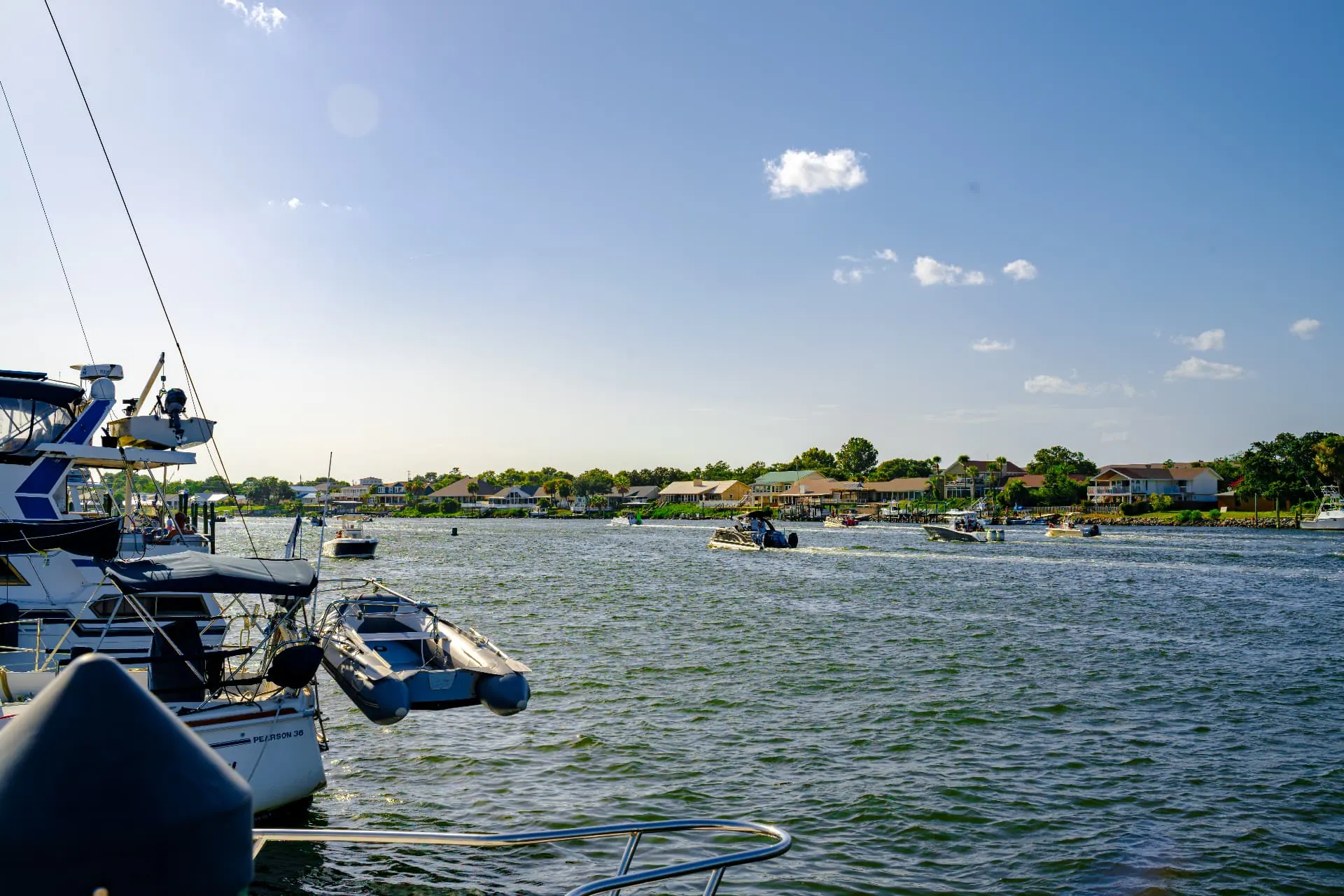 Boats cruising the Intracoastal Waterway on a bright sunny day with homes along the far shoreline