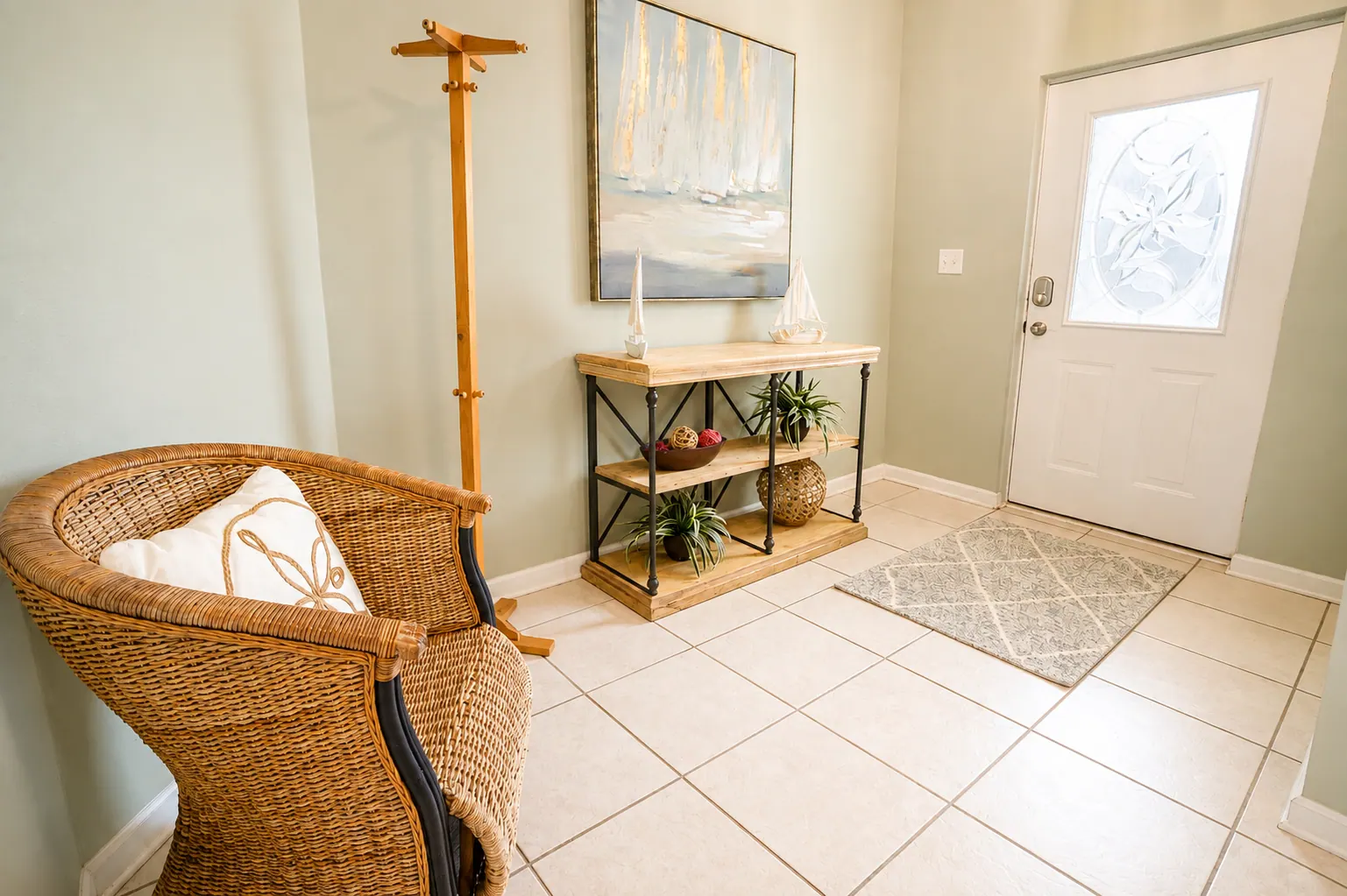 Condo foyer with wicker chair, console table, and sailboat artwork