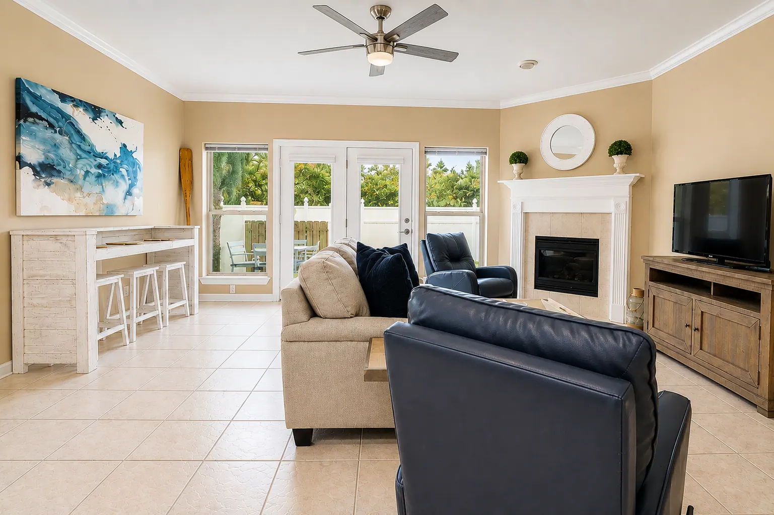 Open condo living room with beige sofa, navy armchairs, fireplace, and glass patio doors
