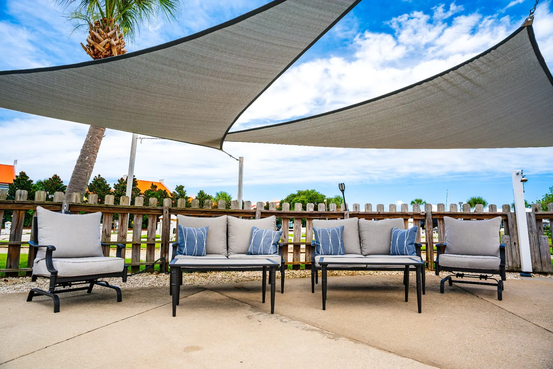 Shaded outdoor lounge seating under sail shades by the marina
